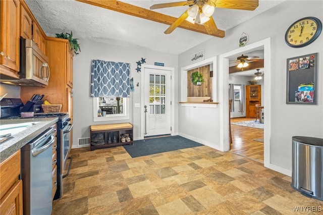 kitchen with stainless steel appliances, brown cabinetry, a textured ceiling, and baseboards