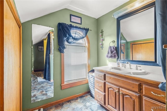 bathroom with baseboards, vaulted ceiling, and vanity