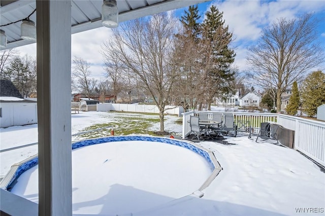 snow covered pool featuring a fenced backyard and outdoor dining space