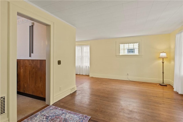 unfurnished room with baseboards, wood finished floors, and a healthy amount of sunlight