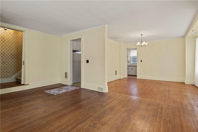 unfurnished living room with visible vents, a notable chandelier, baseboards, and wood finished floors