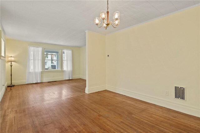 unfurnished room with baseboards, visible vents, wood finished floors, and ornamental molding