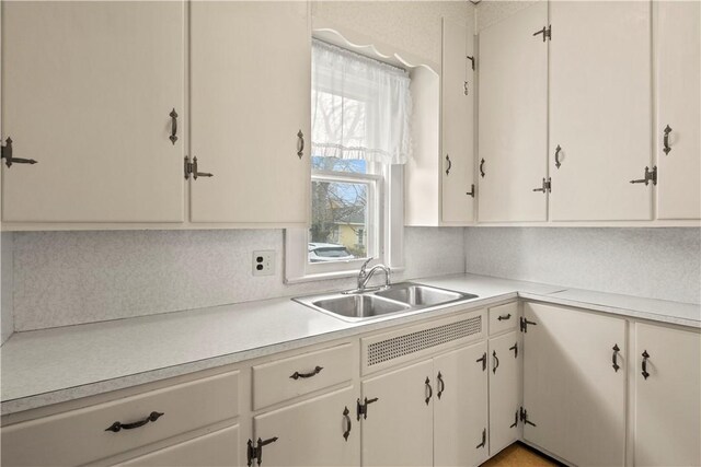 kitchen featuring light countertops, a sink, and white cabinetry