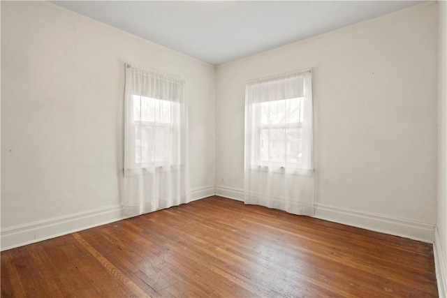 unfurnished room featuring plenty of natural light, baseboards, and hardwood / wood-style flooring