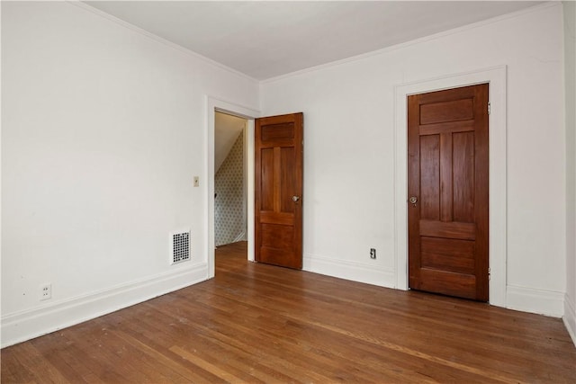 unfurnished room featuring ornamental molding, visible vents, baseboards, and wood finished floors