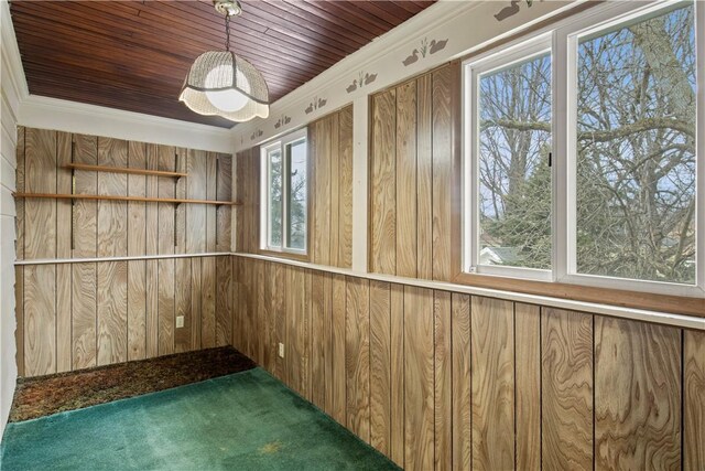 empty room featuring wood ceiling, wooden walls, and crown molding