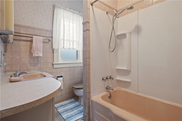 bathroom with toilet, wallpapered walls, tile walls, and vanity