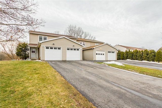 traditional-style house featuring aphalt driveway, a front lawn, and an attached garage