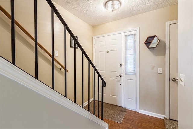 entryway with baseboards, stairway, a textured ceiling, and wood finished floors