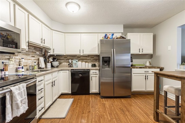 kitchen featuring white cabinets, light wood-style floors, tasteful backsplash, and stainless steel appliances