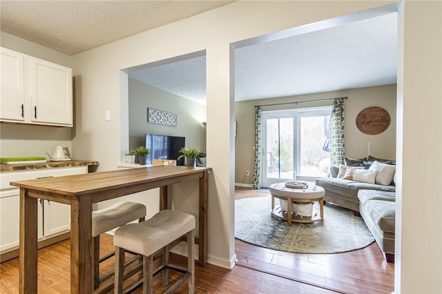 living area with dark wood-style flooring, a textured ceiling, and baseboards