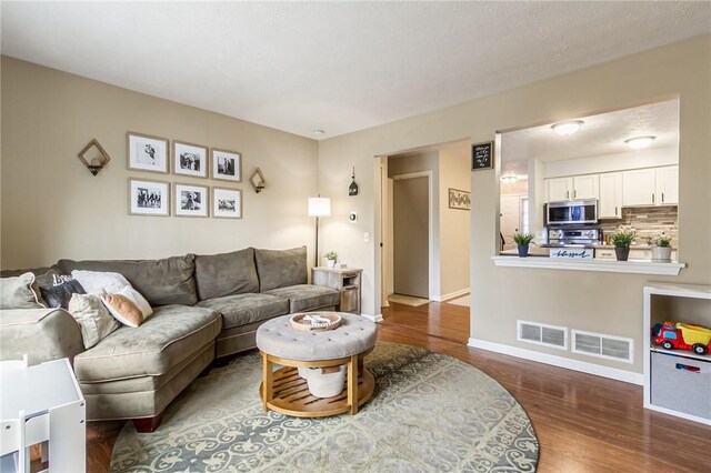 living room featuring visible vents, baseboards, and wood finished floors