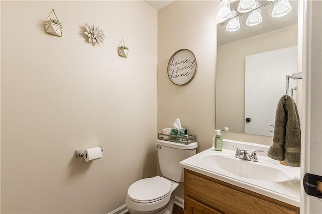 bathroom featuring baseboards, vanity, and toilet