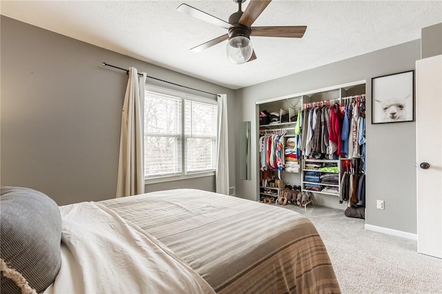 carpeted bedroom featuring a textured ceiling, a closet, a ceiling fan, and baseboards