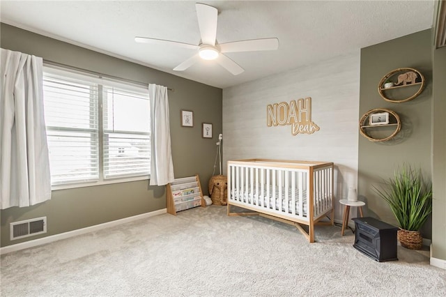 bedroom with visible vents, baseboards, ceiling fan, carpet flooring, and a nursery area