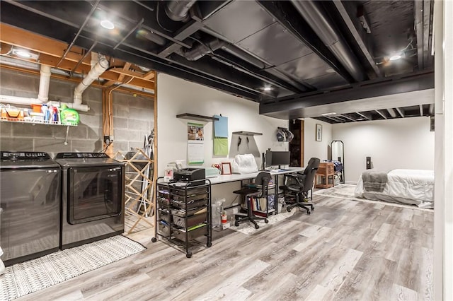 finished basement with concrete block wall, separate washer and dryer, and wood finished floors