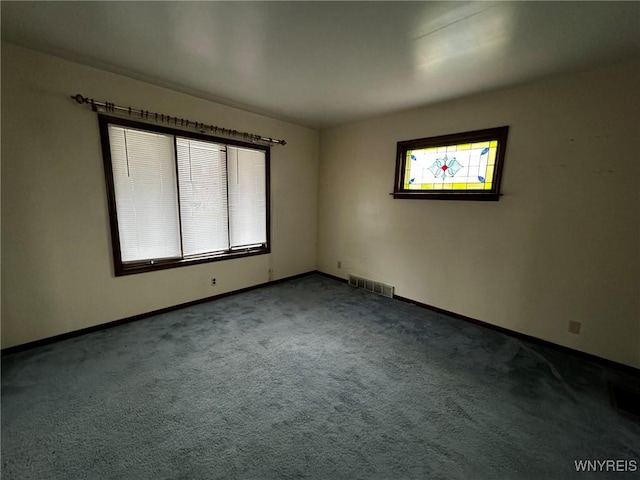 carpeted spare room featuring baseboards and visible vents