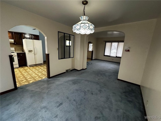 interior space featuring light colored carpet, arched walkways, visible vents, and baseboards