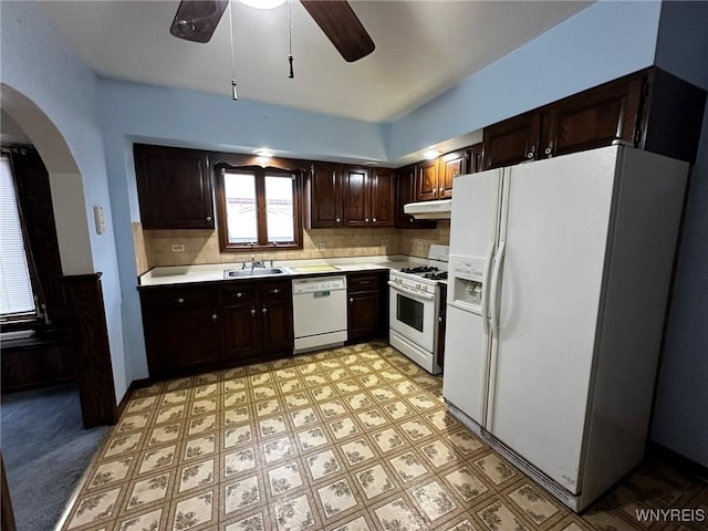 kitchen with arched walkways, light countertops, dark brown cabinetry, white appliances, and under cabinet range hood