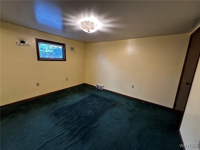 spare room with visible vents, baseboards, and dark carpet