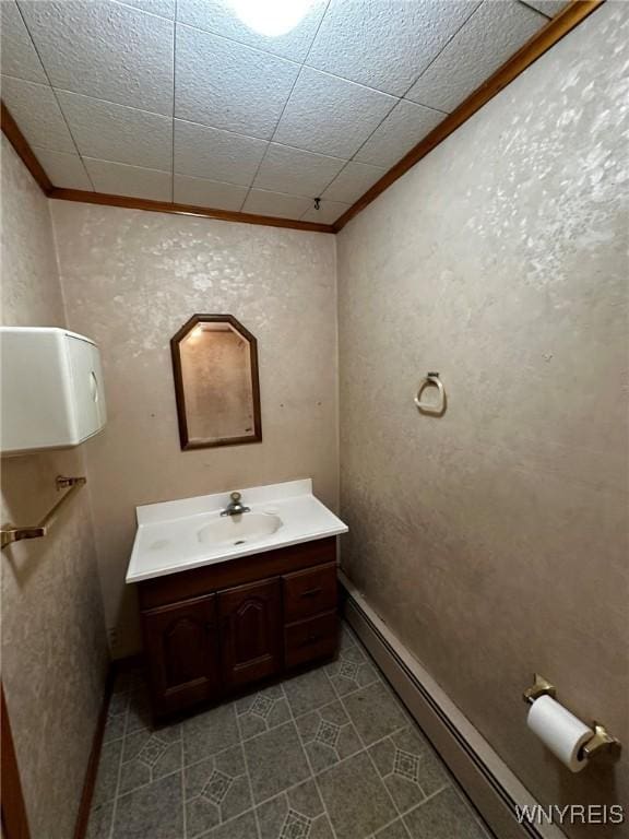 bathroom with a baseboard heating unit, baseboards, crown molding, and vanity