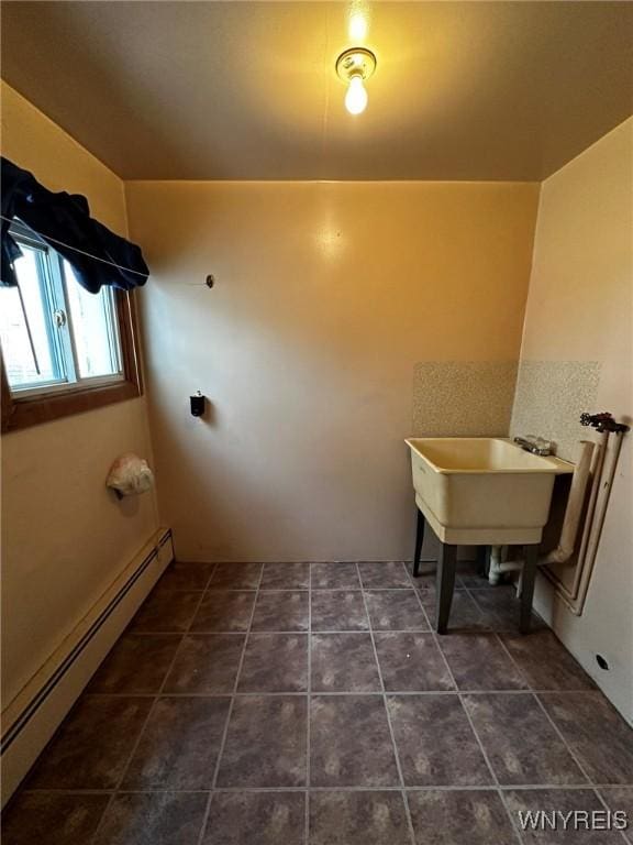 washroom featuring laundry area, a baseboard radiator, and dark tile patterned flooring