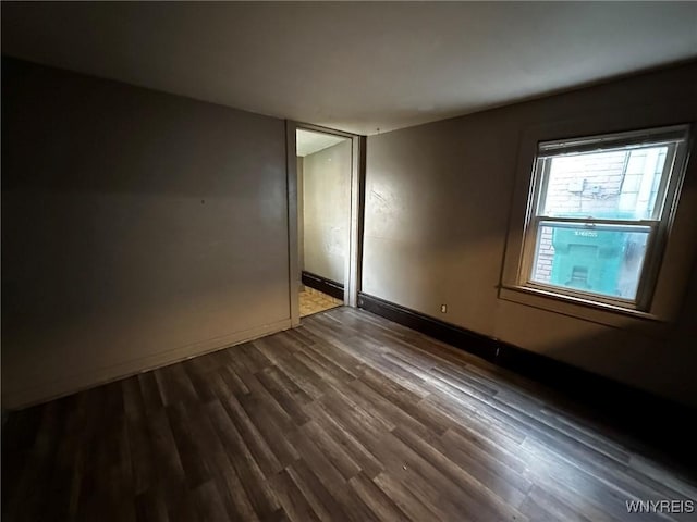 unfurnished room featuring dark wood-style floors and baseboards