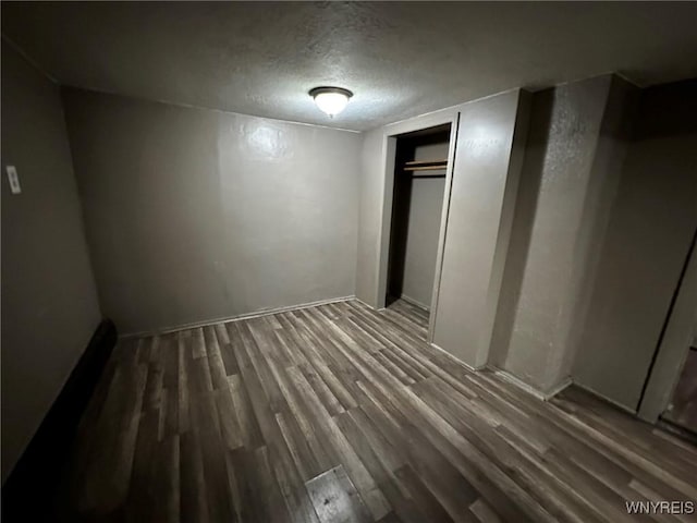 unfurnished bedroom with a closet, a textured ceiling, and wood finished floors