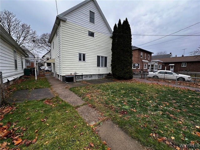 view of property exterior with central air condition unit, fence, and a lawn