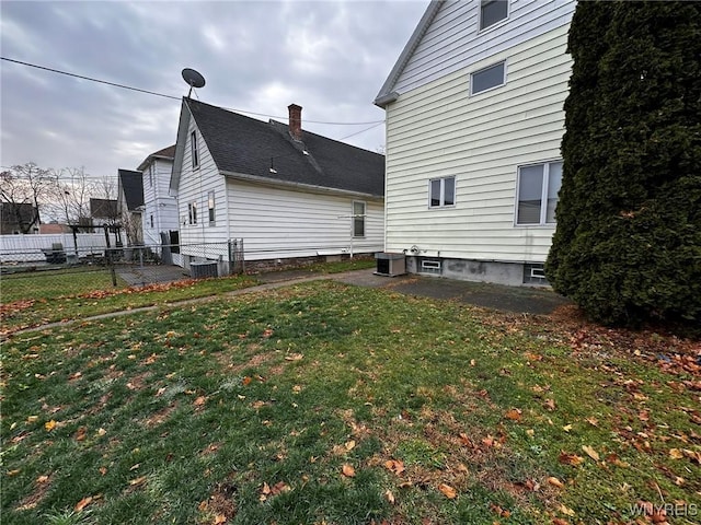 exterior space with central AC, fence, and a lawn