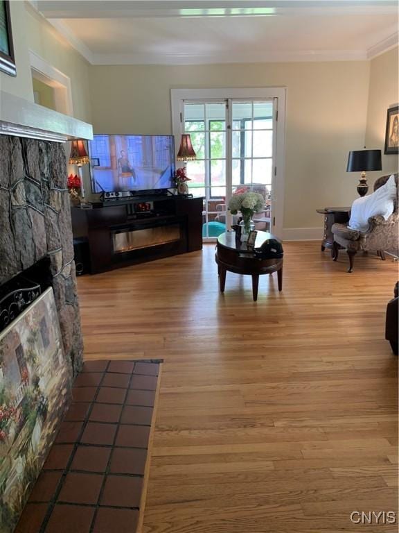 living area featuring baseboards, a fireplace, ornamental molding, and wood finished floors