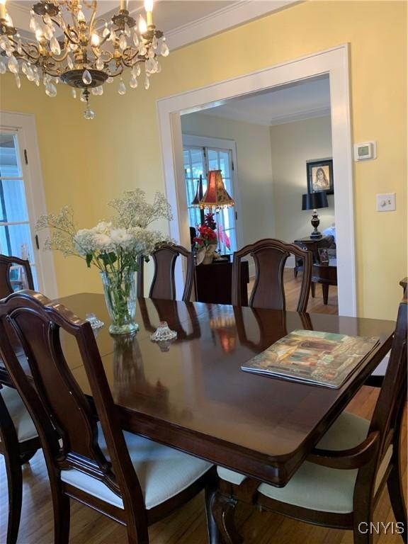 dining room featuring ornamental molding, a chandelier, and wood finished floors