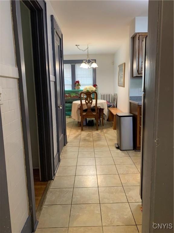 hall featuring light tile patterned floors and a notable chandelier