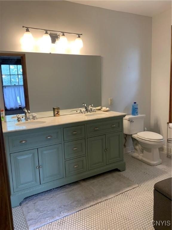 full bathroom featuring toilet, double vanity, a sink, and tile patterned floors