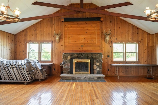 unfurnished living room with wooden walls, a wealth of natural light, and a notable chandelier