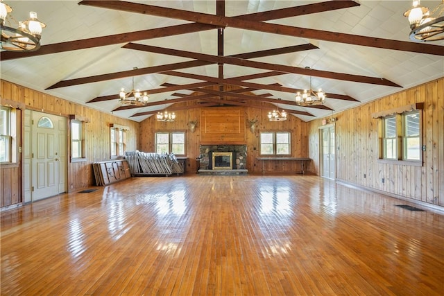 unfurnished living room with a fireplace, a notable chandelier, and wooden walls