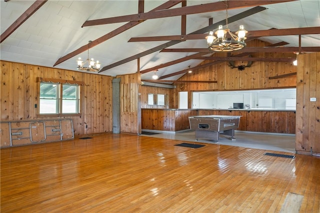 kitchen with beam ceiling, wood walls, hardwood / wood-style flooring, and an inviting chandelier