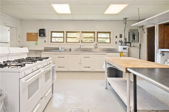 kitchen with white appliances, stainless steel counters, a paneled ceiling, and white cabinets