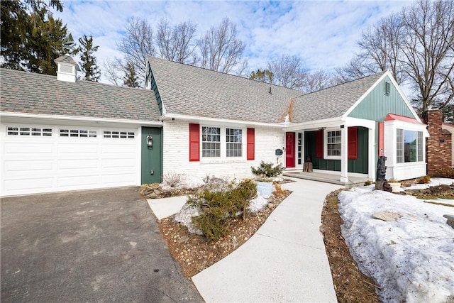 ranch-style house featuring an attached garage, roof with shingles, aphalt driveway, and brick siding