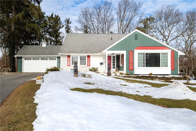 view of front of home with a garage, driveway, a chimney, and a shingled roof