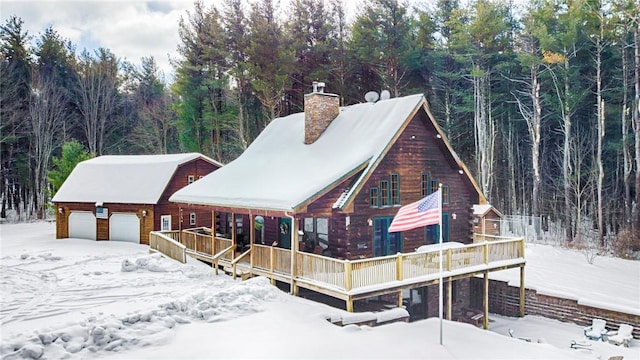 log home with a chimney, a wooded view, and a wooden deck