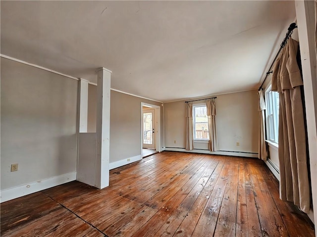 empty room featuring a baseboard radiator, baseboards, and hardwood / wood-style floors