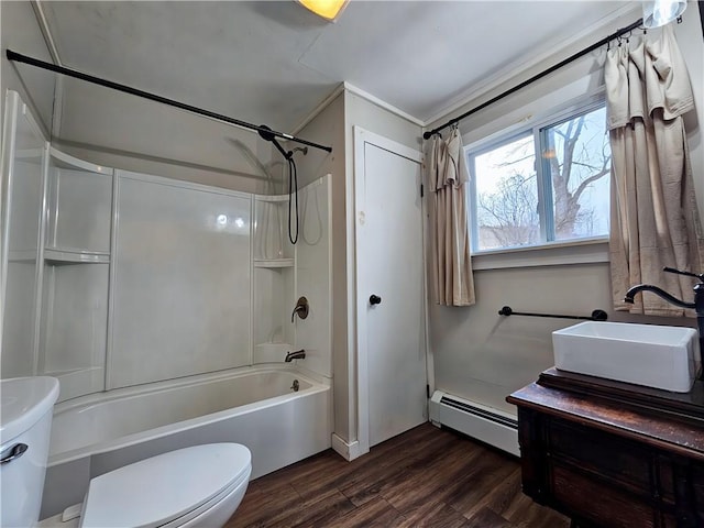 bathroom with a baseboard radiator, toilet, wood finished floors, a sink, and shower / washtub combination