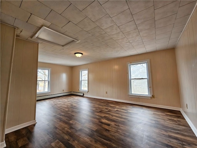 empty room with baseboards, a baseboard radiator, dark wood finished floors, and a healthy amount of sunlight