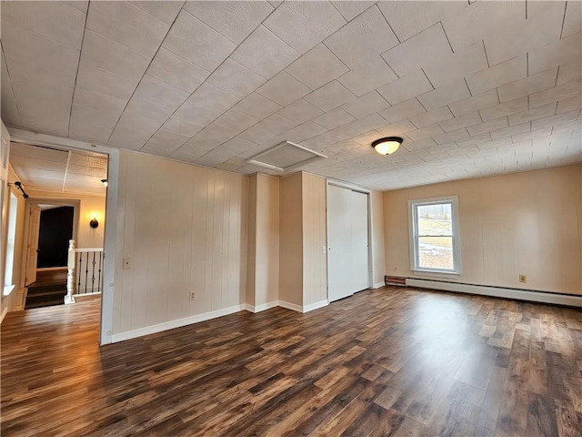 unfurnished room featuring a baseboard radiator, dark wood finished floors, attic access, and baseboards