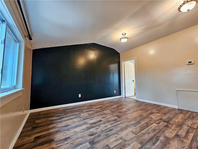 spare room with vaulted ceiling, baseboards, and wood finished floors