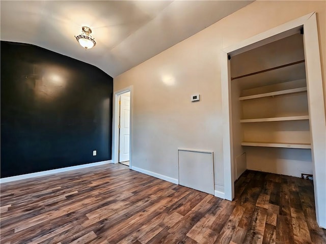 unfurnished room with lofted ceiling, dark wood-type flooring, built in features, and baseboards