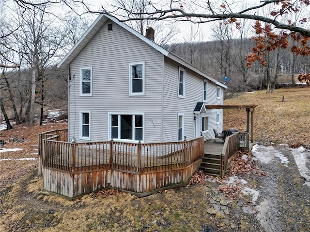 back of property featuring a chimney and a wooden deck