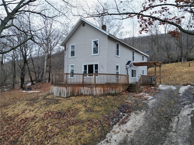 rear view of house featuring a chimney and a wooden deck