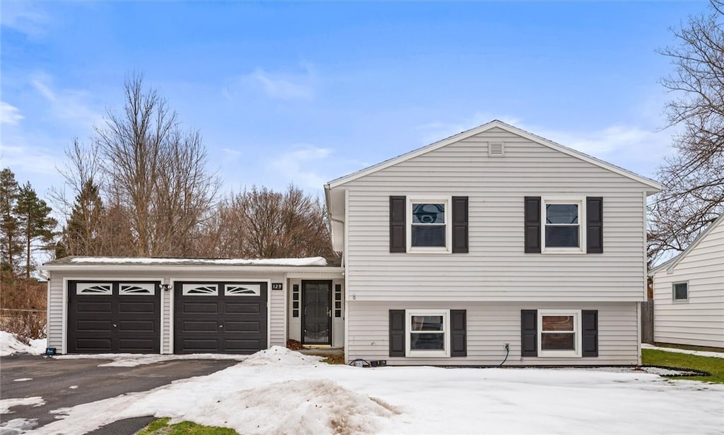 split level home with a garage and aphalt driveway